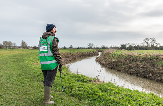 Water Guardian volunteer cleaning litter from a river