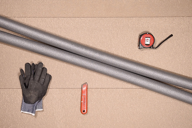 Equipment used for fitting pipe lagging. A tape measure, a knife, safety gloves and some pipe lagging